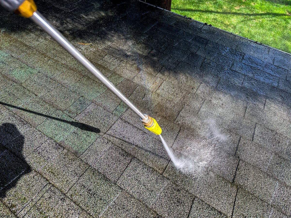 Pressure washer cleaning the roof of a house
