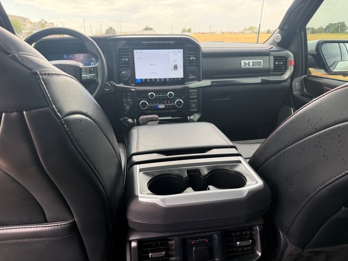 Truck interior showing black leather seats, touchscreen dashboard, and center cup holder console