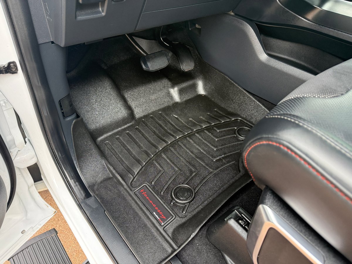 Car interior showing black all-weather floor mats with geometric pattern installed in front and back seats