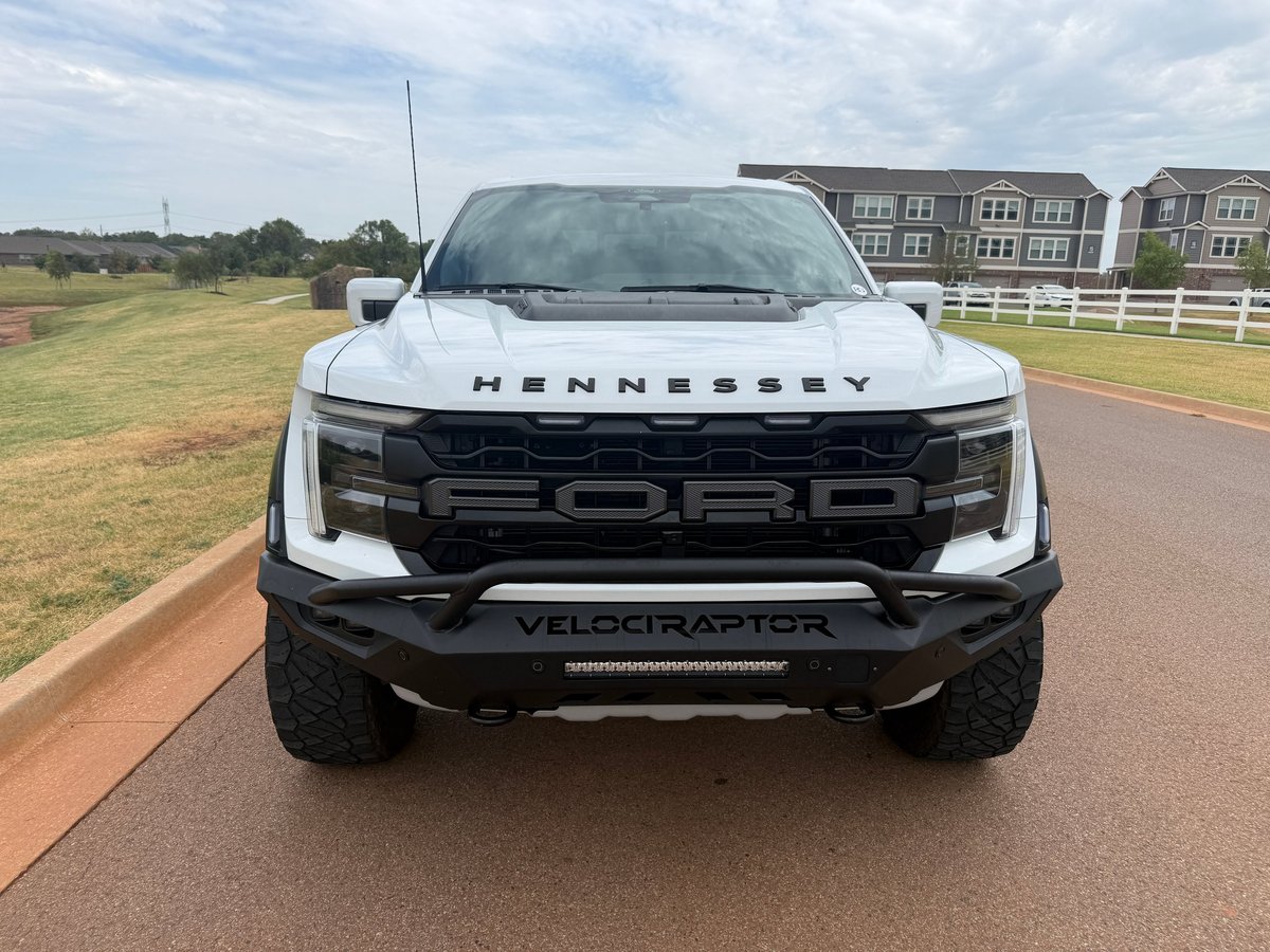 White Hennessey VelociRaptor pickup truck front view on driveway with rural property in background
